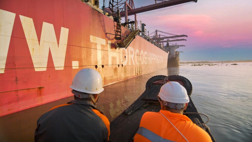 Workers in hard hats beside a bulk carrier at a Vietnamese port
