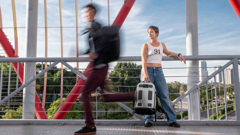 Commercial video still: two runners crossing a red pedestrian bridge
